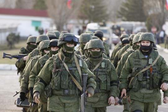 Military personnel, believed to be Russian servicemen, walk outside the territory of a Ukrainian military unit in the village of Perevalnoye outside Simferopol March 3, 2014. Ukraine mobilised for war on Sunday and Washington threatened to isolate Russia economically after President Vladimir Putin declared he had the right to invade his neighbour in Moscow's biggest confrontation with the West since the Cold War. Russian forces have already bloodlessly seized Crimea, an isolated Black Sea peninsula where Moscow has a naval base. REUTERS/Baz Ratner (UKRAINE - Tags: CIVIL UNREST MILITARY POLITICS)